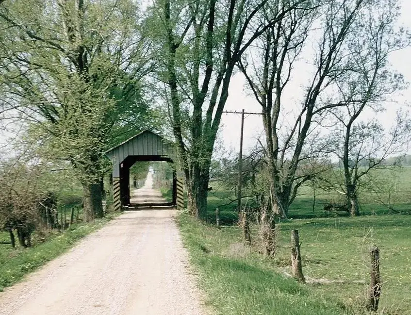 A covered bridge is seen on the side of a road.