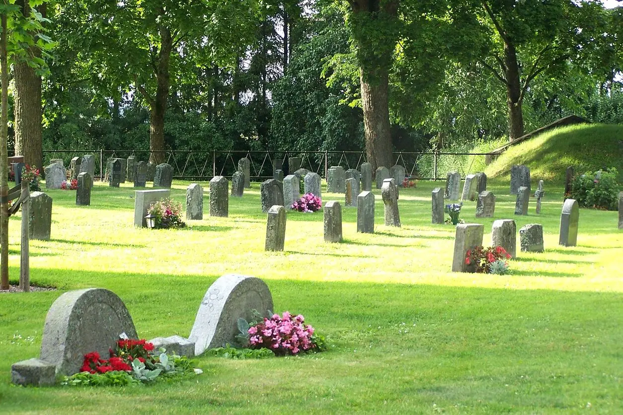 A cemetery with many headstones and flowers on the ground.